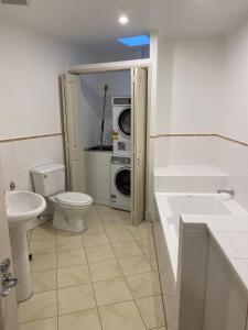 a bathroom with a toilet sink and a washing machine at West End Precinct 2 Bedroom Apartment close to walkway and ocean in New Plymouth