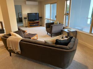 ein Wohnzimmer mit einem braunen Sofa und einem TV in der Unterkunft West End Precinct 2 Bedroom Apartment close to walkway and ocean in New Plymouth