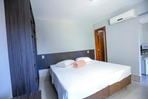 a bedroom with a white bed with a pink hat on it at Vila Nóbrega Residencial in Foz do Iguaçu