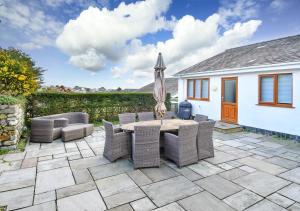 a patio with a table and chairs and an umbrella at 78 Cae Du in Abersoch