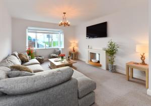 a living room with a gray couch and a fireplace at 78 Cae Du in Abersoch