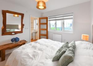 a bedroom with a white bed and a mirror at 78 Cae Du in Abersoch