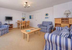 a living room with blue striped chairs and a table at 73 Cae Du in Abersoch