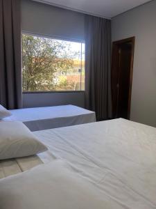 a bedroom with two beds and a large window at Vila Nóbrega Residencial in Foz do Iguaçu