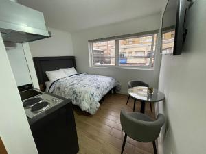 ein kleines Schlafzimmer mit einem Bett und einem kleinen Tisch in der Unterkunft TinyApartments - estudio pleno centro Concepción in Concepción