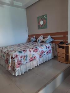 a bedroom with a bed with a floral bedspread at Bahia Flat 301 in Salvador