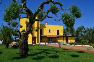 a yellow building with a tree in front of it at Villa D'Anzi B&B in Ginosa