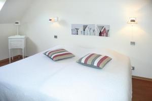 ein weißes Bett mit zwei Kissen darüber in der Unterkunft Holiday Home Plouégat-Guérand - BRE05042-F in Plouégat-Guérand