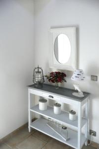 eine weiße Konsole mit einem Spiegel und Blumen in der Unterkunft Holiday Home Plouégat-Guérand - BRE05042-F in Plouégat-Guérand