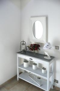 a white console table with a mirror and flowers at Stone House in Brittany near Morlaix Bay in Plouégat-Guérand