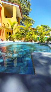 a swimming pool in front of a building with palm trees at Hotel Tabasco in Playa Flamingo