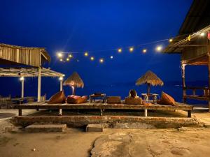 a bench with chairs and umbrellas on the beach at night at The Cosy Koh Phangan in Thong Sala