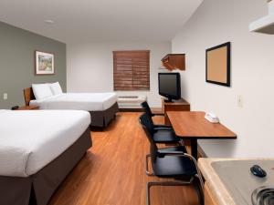 a hotel room with two beds and a desk and a television at Extended Stay America Select Suites - Denver - Aurora in Aurora
