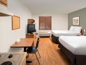 Extended Stay America Select Suites - Indianapolis - Plainfield في بلينفيلد: غرفة فندقية بسريرين ومكتب فيه كمبيوتر