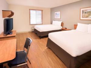 um quarto de hotel com duas camas e uma secretária e uma televisão em Extended Stay America Select Suites - Fayetteville - Fort Bragg em Fayetteville