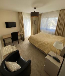 een hotelkamer met een bed, een stoel en een bureau bij Hotel Exquisit in Minden