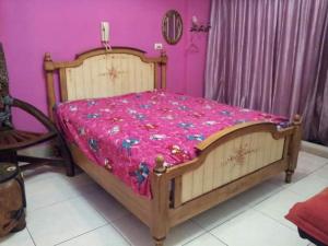 a bedroom with a wooden bed with a pink sheets at Hualien Seaside B&B in Hualien City