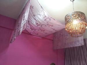 Habitación rosa con lámpara de araña y pared de color rosa. en Hualien Seaside B&B en Hualien