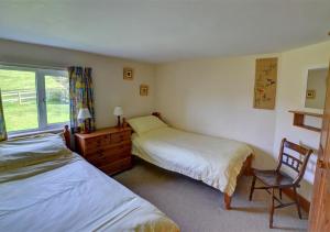 a bedroom with two beds and a chair and a window at Black Patch in Norton