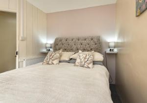 1 dormitorio con 1 cama blanca grande con almohadas en Bryn Tirion, en Llanbedrog