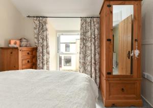 a bedroom with a bed and a dresser and a window at Bryn Tirion in Llanbedrog