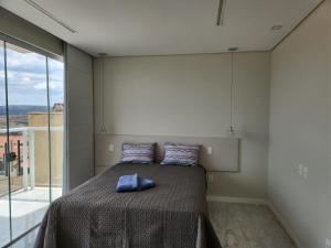a bedroom with a bed and a large window at Apto inteiro de luxo em Diamantina in Diamantina
