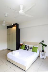 een wit bed met groene kussens in een slaapkamer bij LOVELY & COZY HOME @ MIDILLS GENTING in Genting Highlands