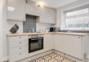 a kitchen with white cabinets and an oven at Bwthyn Bach in Ferryside