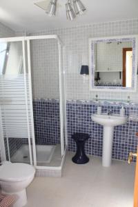 Baño de azulejos azules con aseo y lavamanos en Orzola Para Descansar, en Orzola