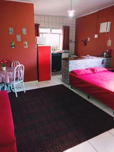 una camera da letto con pareti rosse e una cucina con tavolo di Apartamentos IFAT - RJ a Mangaratiba
