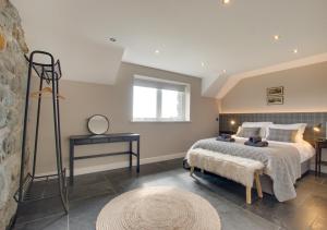 um quarto com uma cama, uma mesa e uma janela em Bwthyn Ednyfed em Criccieth