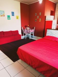 una camera da letto con pareti rosse, un letto rosso e un tavolo di Apartamentos IFAT - RJ a Mangaratiba