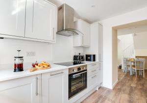 a kitchen with white cabinets and a plate of fruit on the counter at Bwthyn Clyd in Llanddyfnan