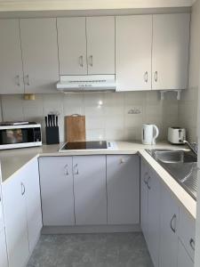 a white kitchen with white cabinets and a sink at Portarlington Holiday Apartment in Portarlington