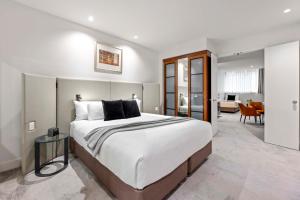 a bedroom with a large bed and a living room at Peppers Waymouth Hotel in Adelaide
