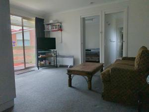 a living room with a couch and a table and a tv at Portarlington Holiday Apartment in Portarlington