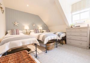 a bedroom with two beds and a dresser at Chart House in Tenby