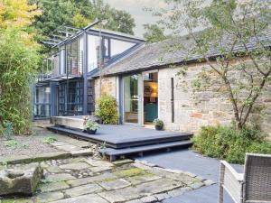 a stone house with a porch and a patio at Tigh Nam Muc in Loanhead