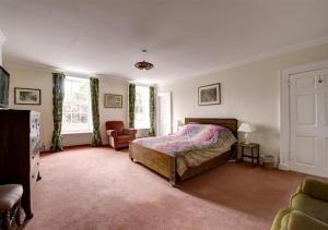 a bedroom with a bed and a chair and windows at Clynderwen House in Pembroke