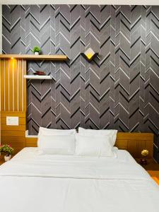 ein Schlafzimmer mit einem weißen Bett und einer Wand in der Unterkunft Milaano Orchids, Service Villa, Kammana Mananthavady in Wayanad
