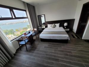 Habitación de hotel con cama y ventanas grandes. en Novatel Hotel & Apartment, en Hai Phong