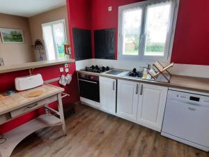 a kitchen with red walls and white appliances at Maison de plain-pied avec jardin clôturé, proche Thermes St Roch - 3 chambres, WiFi, cuisine équipée - FR-1-541-46 in La Roche-Posay