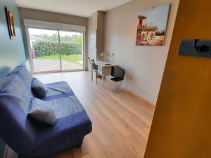 a living room with a blue couch and a desk at Maison de plain-pied avec jardin clôturé, proche Thermes St Roch - 3 chambres, WiFi, cuisine équipée - FR-1-541-46 in La Roche-Posay +2 photos
