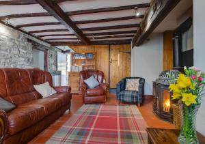 sala de estar con sofá de cuero y estufa de leña en Cwm Hesgen, en Rhydymain