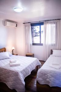 1 dormitorio con 2 camas y ventana en Casa Di Mattoni en Bento Gonçalves