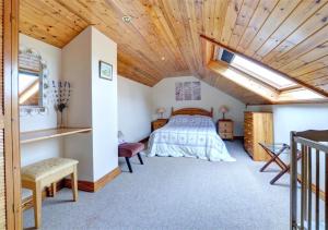 a bedroom with a bed and a wooden ceiling at Tyn Coed in Moelfre