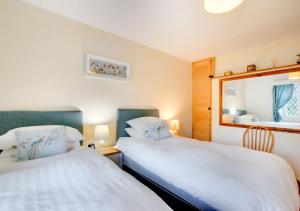 a bedroom with two beds and a mirror at The Lodge in Pwllheli