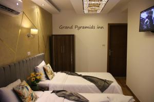 a hotel room with two beds and a tv at Grand Pyramids Inn in Cairo