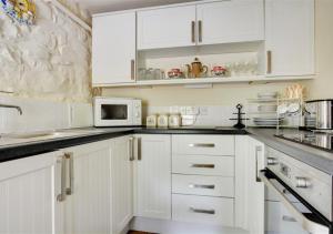 サンダースフットにあるStable Cottageの白いキッチン(白いキャビネット、電子レンジ付)