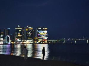 un hombre y una mujer de pie en la playa por la noche en JJ House Gwangan Beach en Busan